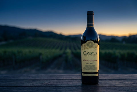Caymus Cabernet Sauvignon bottle in a Napa Valley vineyard at dusk